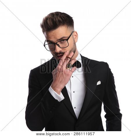 elegant man wearing a tuxedo, smoking a cigarette on white background 