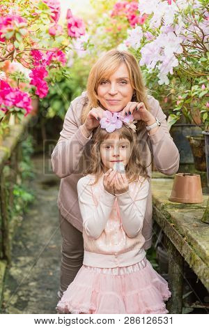 Mother And Daughter Carying Plants, Spending Time Together In Greenhouse. Azalea Flowers. Botanical 