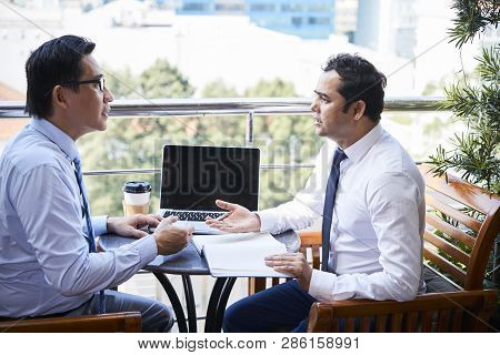 Two Mature Office Workers Sitting At The Table In Cafe With Opened Dayplanner And Discussing New Bus
