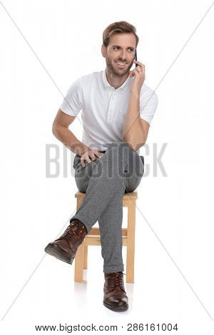 seated casual man talks on the phone on white abckground