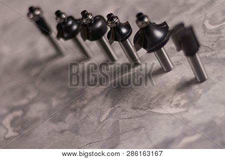 Row Of Lot Of Steel Router Bits For Milling Cutter On Old Broken Worn Gray Concrete Floor With Copy 