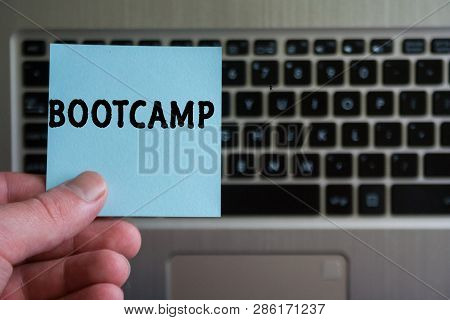 Word Bootcamp On Sticky Note Hold In Hand On Laptop Keyboard Background.