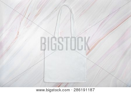 Reusable White Fabric Bag On Marble Texture With Natural Pattern. Flat Lay