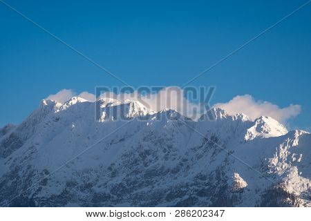 Snow Covered Mountain Range With Mountains Grimming, Schartenspitze And Steinfeldspitze On A Sunny W