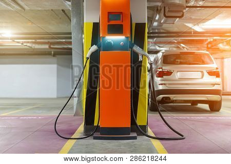 Electric Car Fast Charging Station At Indoor Underground Parking. Power Supply Point Network For Hyb