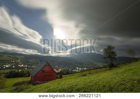 Summer Night Mountain Panorama. Small House Cottage On Steep Mountain Slope On Dramatic Evening Sky 