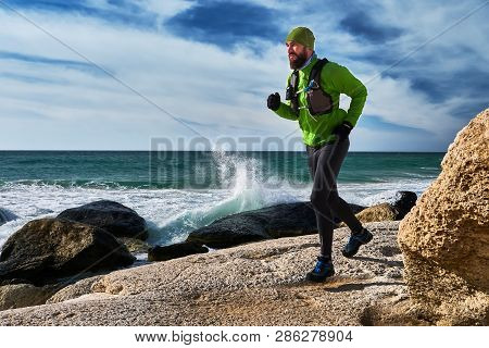 Athlete Guy Runs Along The Seashore On A Sunny Day. Trail Running. Mangystau Peninsula. Kazakhstan