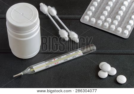 Still Life With A Thermometer And Pills. A Photo Of A Fragmented Table At A Bedside Table For A Pati