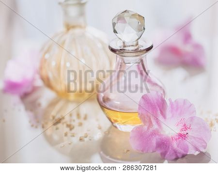 Spa Still Life With Perfume And Aromatic Oils Bottles Surrounded By Flowers, On Light Background