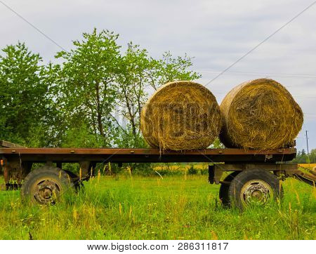 Two Twisted Hay Rolls On A Cart In The Field.