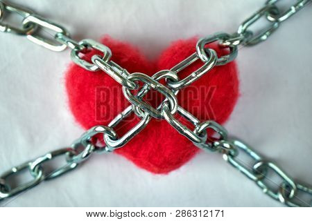 Red Wool Heart Locked With Metal Chain On White Bed Sheet