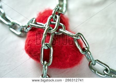 Red Wool Heart Locked With Metal Chain On White Bed Sheet