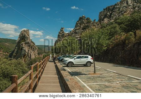 Cars Parked Next To Road Through Rocky Cliffs