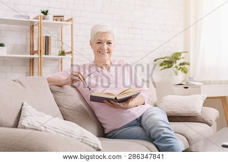 Learning Foreign Languages. Cheerful Senior Woman Reading Educational Book At Home