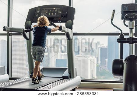 A Little Boy Is Running On The Treadmill. Childrens Sport Concept