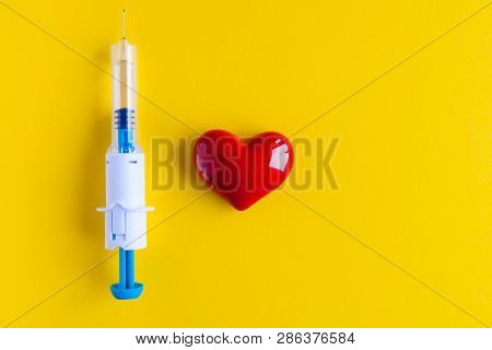 Volumetric Heart Shape With A Syringe On A Yellow Background. Congenital Heart Defect