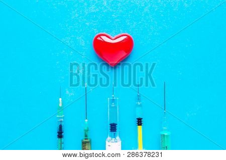 Volumetric Heart With Syringes On A Blue Background. The Concept Of Supporting Patients With Heart D