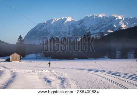 Woman Running Cross-country Skiing In Bad Mitterndorf With Nice View To Mountain Grimming On A Sunny