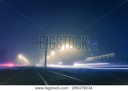 Road With Poles With High-voltage Wires And Tram Tracks Or Tram Rails , Evening Fog On The Streets, 
