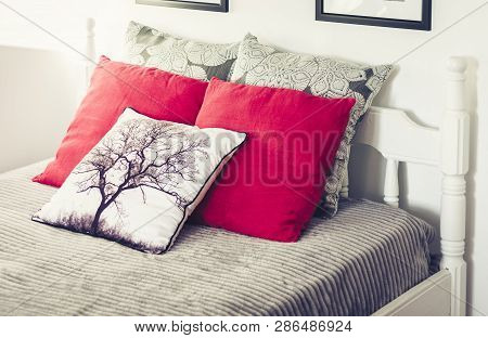 White Wooden Carved Bed With Gray Bedspread And Red Pillows