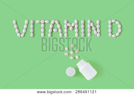 Pills Dropped In Shape Of Words Vitamin D From Bottle On Green Background. Flat Lay, Top View. Healt