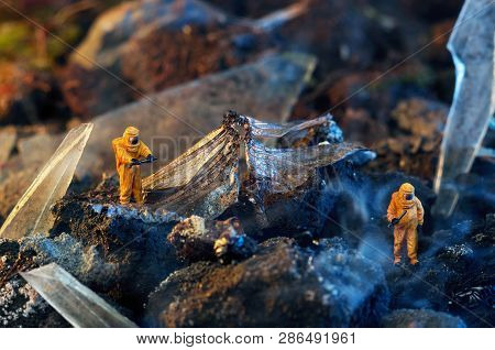Conceptual photo of toy people in hazmat suits and wings of a dead dragonfly. Environmental disaster concept.