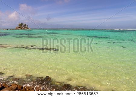 Beautiful Beach On Island Mahe, Seychelles. View On A Turquoise Lagoon And An Inhabited Island In Th