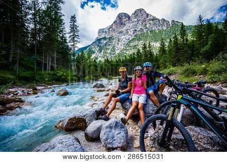 Tourist cycling in Cortina d'Ampezzo, stunning rocky mountains on the background. Family riding MTB enduro flow trail. South Tyrol province of Italy, Dolomites.