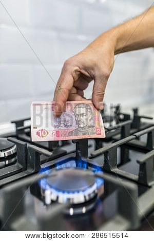Cooktop With Burning Gas Ring With Hands Holding Money 10 Uah Hryvnas For Combustion At Home.