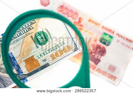 Hundred Dollar Under A Magnifying Glass On The Bacdrop Euro And Ruble Banknotes. Сoncept Of The Main