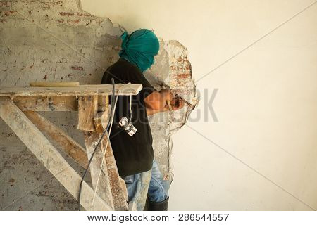 Worker Removing The Plastered Cement Surface On The Bricklayer Wall