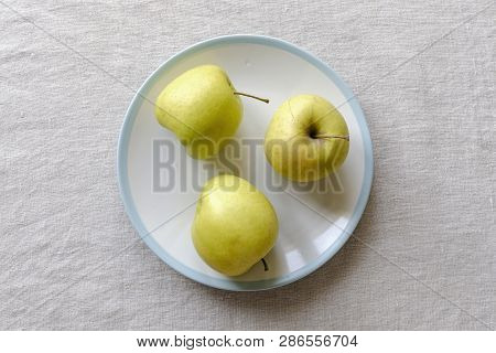 Ugly Food Concept With Misshapen Fresh Healthy Juicy Golden Apples On A Plate Over A Textured White 
