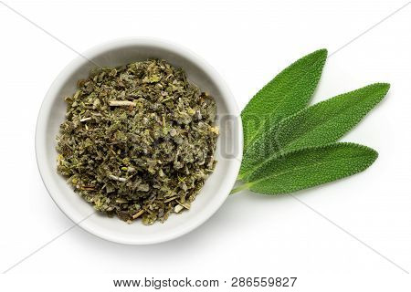 Dried Rubbed Sage In A White Ceramic Bowl Next To Fresh Sage Leaves Isolated On White From Above.