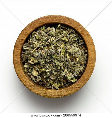 Dried Rubbed Sage In A Dark Wood Bowl Isolated On White From Above.