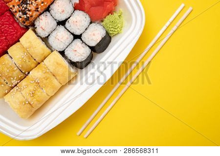 Top View On Sushi Set At Colored Background. Plate With Rolls, Ginger And Vasabi