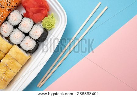 Top View On Sushi Set At Colored Background. Plate With Rolls, Ginger And Vasabi