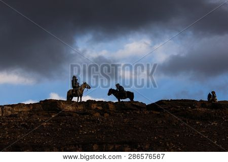 SAGSAY, MONGOLIA - SEP 28, 2017: Berkutchi - Eagle Hunters traditional clothing, while hunting to the hare holding a golden eagles on his arms in desert mountain of Western Mongolia.