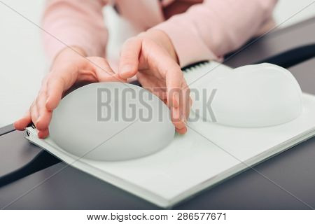 Breast Augmentation. Woman Chooses Breast Implant, Close-up Silicone Breast Implant