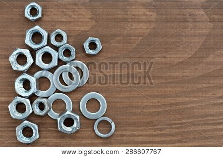 Several Various Metal Fasteners For Construction. Nuts, Washers And Washer-grover, Close-up On A Woo