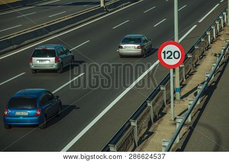 Cars Passing Through Multi Lane Highway And Speed Limit Signpost, On Sunset In Madrid. Capital Of Sp