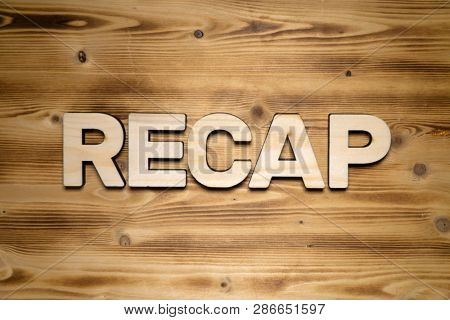 RECAP word made of wooden block letters on wooden board.