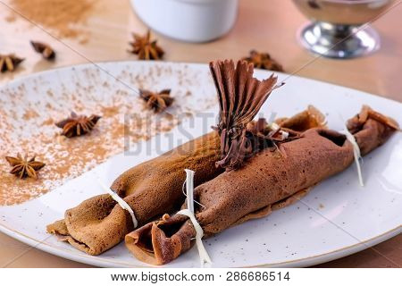 Chocolate Russian Pancakes, Blini With Curd Filling On The Plate. Served With A Cup Of Tea And Choco