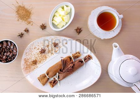 Chocolate Russian Pancakes, Blini With Curd Filling On The Plate. Served With A Cup Of Tea And Choco