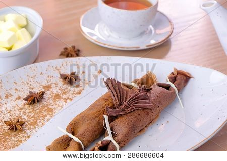 Chocolate Russian Pancakes, Blini With Curd Filling On The Plate. Served With A Cup Of Tea And Butte