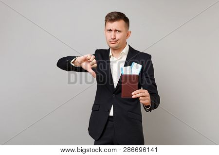 Dissatisfied Young Business Man In Classic Suit Showing Thumb Down, Holding Passport, Boarding Pass 