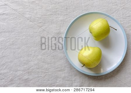 Ugly Food Concept With Misshapen Fresh Healthy Juicy Golden Apples On A Plate Over A Textured White 