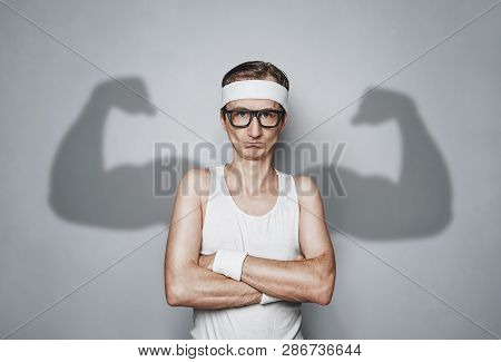 Funny Sport Nerd With Shadow Muscle Arms Over Gray Wall With Copy Space