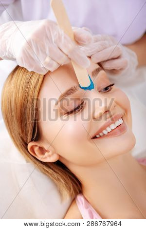 Young Photo Model Smiling While Waxing Line Between Eyebrows