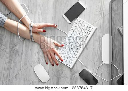 Compulsive Computer Use, A Slave To New Technologies.
A Woman With Bound Hands Writes On A Computer 