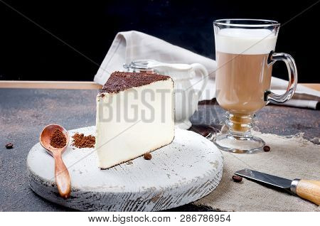 Latte Coffee With Froth In A High Glass Goblet, Piece Of Soft Cheese Sprinkled With Ground Coffee Or